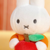 Plush toy resembling a white rabbit with a carrot on a blurred background