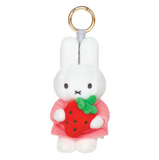Plush keychain of a white rabbit character holding a strawberry on a white background