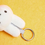 White plush dog toy with a gold ring on a yellow background