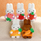 Five small rabbit figurines holding fruits and vegetables on a textured surface.