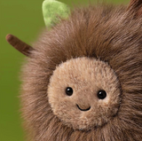 Close-up of a plush lion toy with brown faux fur, a beige stitched face, black eyes, and a small green ear, set against a soft green background.