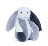 A plush bunny toy with long floppy ears in pale blue, lavender-gray, and dark navy, with a light pink nose, photographed on a clean white background.