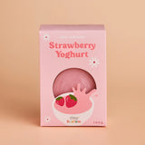 Pink packaging of strawberry yoghurt with a bowl and strawberries on a beige background