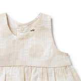 Close-up of a beige baby dress with a brand logo on a white background