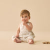 Baby in a white outfit sitting on a beige background
