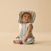 Baby wearing a striped romper and hat on a beige background