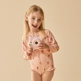 Young girl in a pink outfit holding a pink camera against a beige background