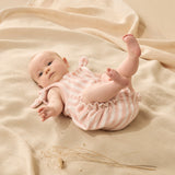 Baby in a pink striped outfit lying on a beige blanket