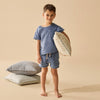 Child holding a pillow with pillows stacked on the floor against a beige background