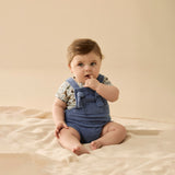 Baby wearing a blue romper with a beige background