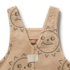 Beige children's overalls with smiley face designs on a white background