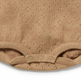 Close-up of a beige baby romper with textured pattern on a white background