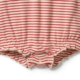 Close-up of a baby romper or bodysuit with horizontal red and cream stripes, featuring a ruffled hem and snap closures at the crotch.