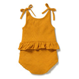A mustard yellow baby romper with eyelet knit fabric, featuring shoulder tie straps, a ruffled hemline, and a scalloped bottom edge, shown flat on a white background.