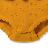 Close-up of a mustard yellow knit baby bodysuit with a scalloped leg opening and three snap buttons.