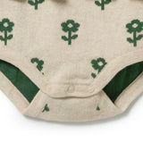 Close-up of a cream-colored knitted baby bodysuit with a green knit floral pattern and snap closures at the crotch.