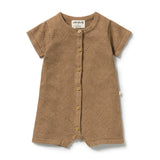 A short-sleeve baby romper in a warm brown color, featuring a textured knit pattern, button-up front, and a visible 'urban family' brand label at the collar.