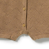 Close-up of a brown knit baby cardigan or romper with a diamond knit pattern, three wooden buttons, and snap closures at the crotch.