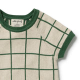 Close-up of a short-sleeve knit top with a cream base and dark green windowpane grid pattern, featuring a dark green ribbed crew neck and sleeve cuffs. The brand label reads 'sophia & co'.