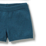 Close-up of a teal blue knit garment, showing the ribbed waistband and leg openings on a white background.