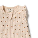 A close-up of a ribbed cream-colored baby top with small brown polka dots and ruffled shoulder details, showing the brand label 'witty & friendly'.