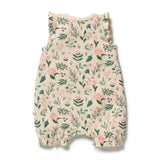 A sleeveless baby romper in a cream-colored ribbed fabric with an all-over green and pink floral print, featuring ruffled shoulder straps and leg cuffs, shown flat on a white background.