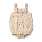 A baby romper in cream-colored ribbed gauze fabric with a small brown leaf print, featuring ruffled straps and a ruffled neckline, laid flat on a white background.