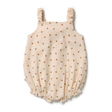 A cream-colored ribbed baby romper with a brown polka dot pattern and ruffled straps, shown flat on a white background.