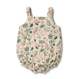 A baby bubble romper in a beige crinkle gauze fabric with a green and pink floral print, featuring shoulder straps and an elasticized bottom.