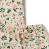 Close-up of a two-piece pajama set featuring a cream-colored ribbed fabric with a green and pink floral print, including a top and matching shorts with an elastic waist and drawstring.