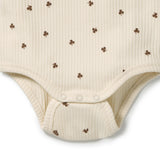 Close-up of a cream-colored ribbed bodysuit with small brown shamrock motifs, featuring three snap buttons at the crotch.