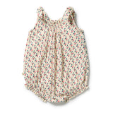 A sleeveless baby romper in a warm cream fabric with a dense, all-over small floral print in pink, green, and blue, featuring a gathered smocked bodice and ruffled shoulder and leg details.