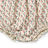 Close-up of a cream-colored crinkled fabric garment with a small pink and dark green floral print and ruffled trim at the bottom.