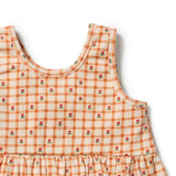 Close-up of a sleeveless children's dress with an orange and cream gingham pattern and small red rose motifs, shown on a white background.