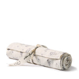 A rolled-up muslin baby blanket with a gray and black cat pattern, tied with a cream ribbon printed with cat illustrations and the brand name 'velvet + fur').