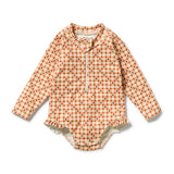 A baby long-sleeve bodysuit in a warm orange and beige gingham pattern with small red square motifs, featuring a ruffled hem and snap closures.