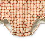 Close-up of a baby romper or bodysuit with an orange and cream gingham check pattern, decorated with small red rose motifs, featuring three snap buttons at the crotch and ruffled leg hems.