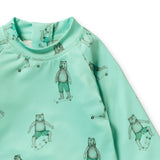 A close-up of a mint green long-sleeve top with an all-over print of teddy bears wearing green striped shorts and skateboarding, shown against a plain white background.