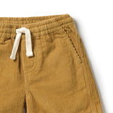 Close-up of mustard yellow corduroy pants with a white drawstring waistband, showing the ribbed fabric texture and side pocket stitching on a white background.