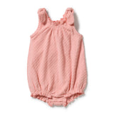 A baby girl's pink textured bubble romper with ruffled shoulder straps and a ruffled hem, laid flat on a white background.