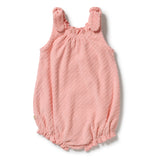 A baby romper in a soft, textured dusty pink fabric, featuring ruffled shoulder straps and a ruffled hem, laid flat on a white background.