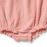 Close-up of a baby romper or bodysuit in a soft dusty pink color, showing the textured fabric and elastic ruffled leg openings with snap closures.