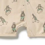 Close-up of a cream-colored baby romper with a front zipper, featuring an all-over print of bears in green striped shorts skateboarding.