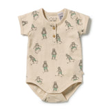 A short-sleeve baby bodysuit in cream-colored organic cotton, featuring an all-over print of cartoon bears wearing green shorts and rolling skateboards. The bodysuit has a three-button henley neckline and is photographed flat on a white background.
