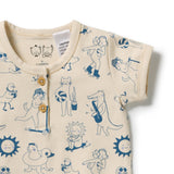 A close-up of a baby short-sleeve henley top in cream with a blue cartoon animal and sun print, featuring a button placket.