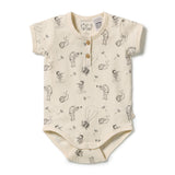 A short-sleeve baby bodysuit in cream-colored cotton, featuring a black line-art print of cartoon animals and small wooden snap buttons at the collar.