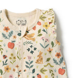 Close-up of a baby sleep sack with a cream-colored base and a colorful floral and nature print featuring strawberries, a rabbit, leaves, and ladybugs.