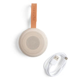 Round beige speaker with leather strap and USB cable on a white background