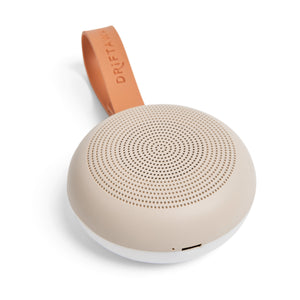 Beige portable speaker with brown leather strap on a white background