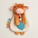 Plush cow toy with colorful elements on a light background
